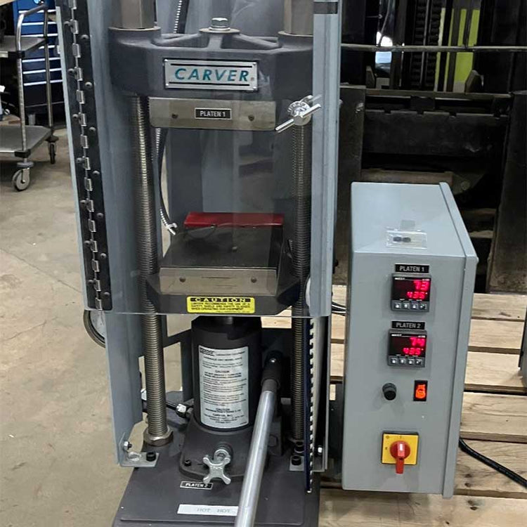 Industrial press machine with 'Carver' branding in a workshop setting